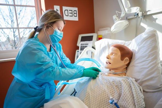 Nursing student works with simulation lab equipment.